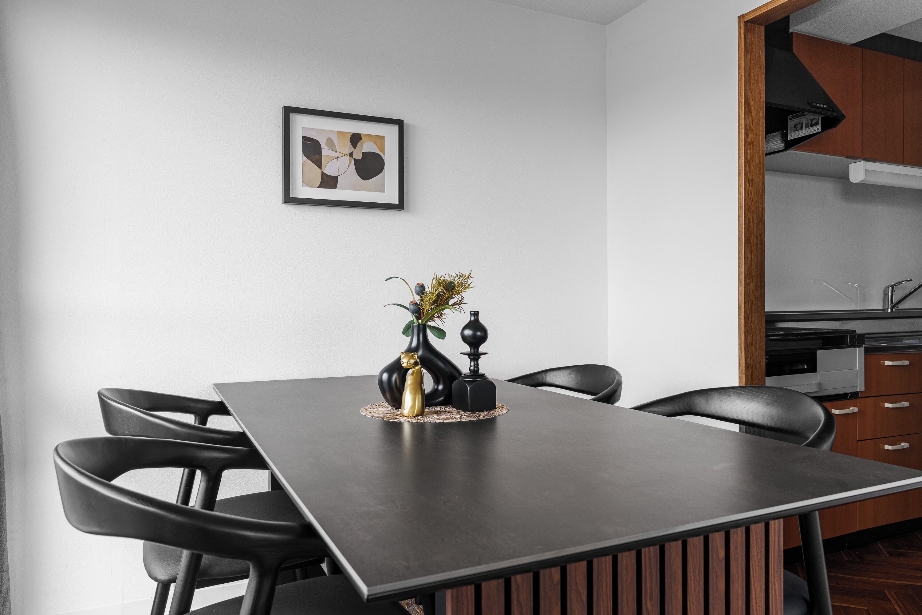 A modern dining area with a dark table, black chairs, and a vase with flowers.