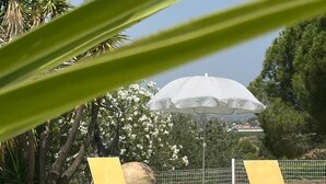 A swimming pool with two yellow lounge chairs and a white umbrella.