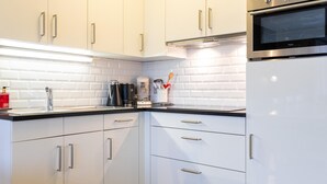 A modern kitchen with white cabinetry, stainless steel appliances, and a black countertop. - Spacious 2-Bedroom Apartment Near the Sea (Blankenberge)