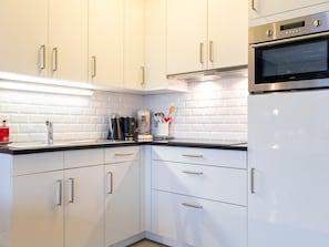 A modern kitchen with white cabinetry, stainless steel appliances, and a black countertop.