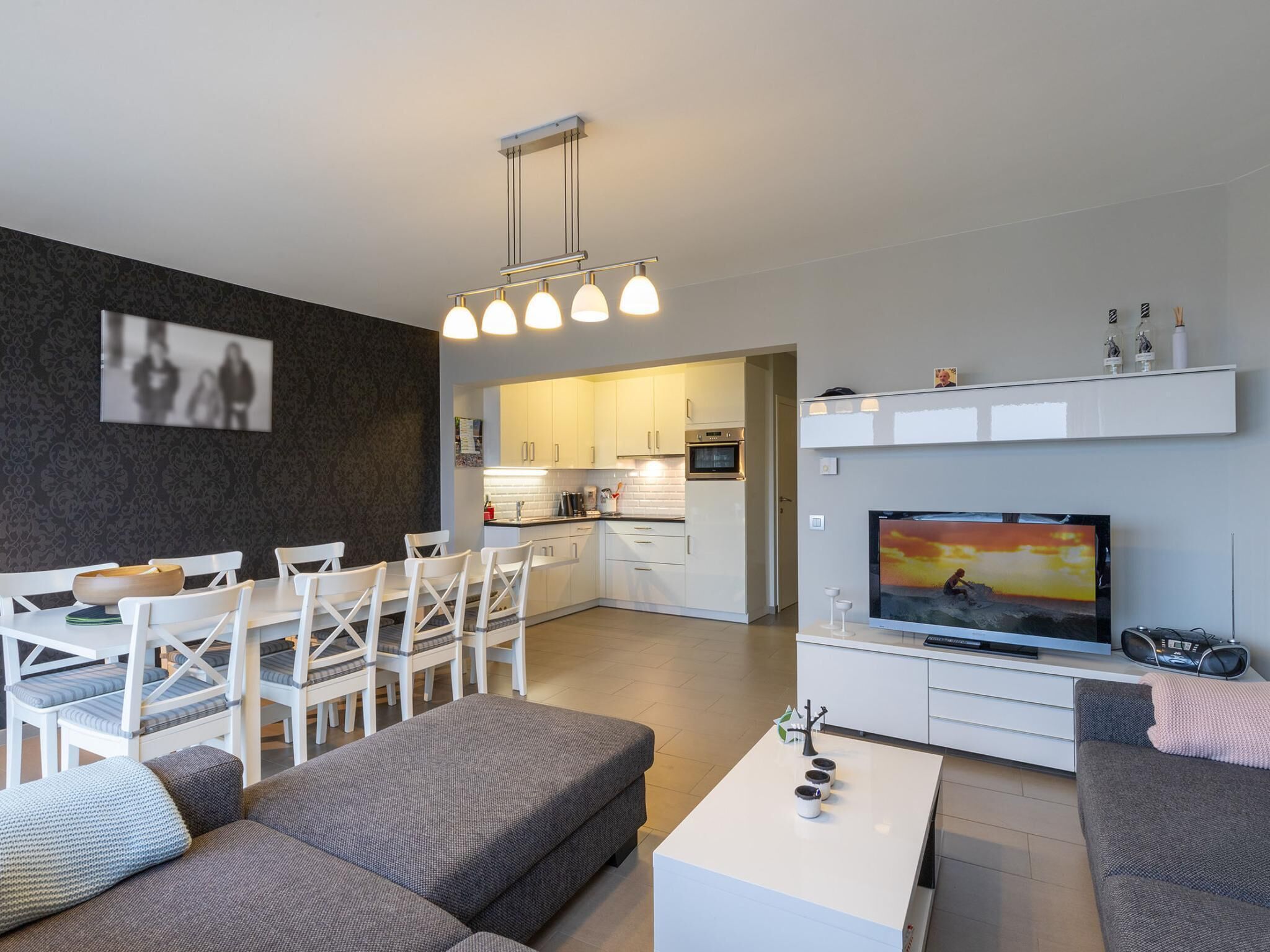 Un salon moderne avec un téléviseur, un canapé et un coin repas.