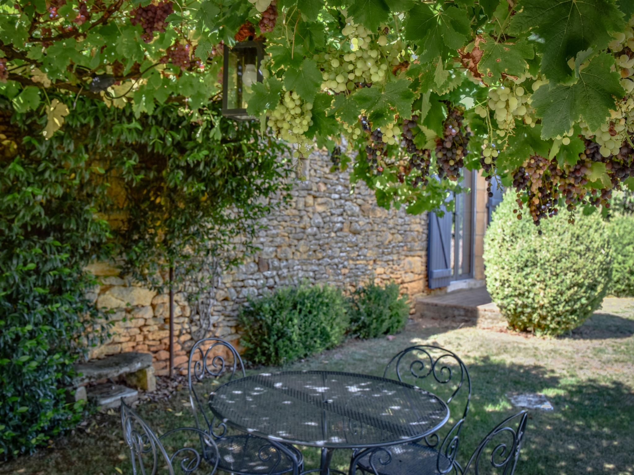 Eine Steinsäule mit einem Metalltisch und -stühlen in einem Garten.