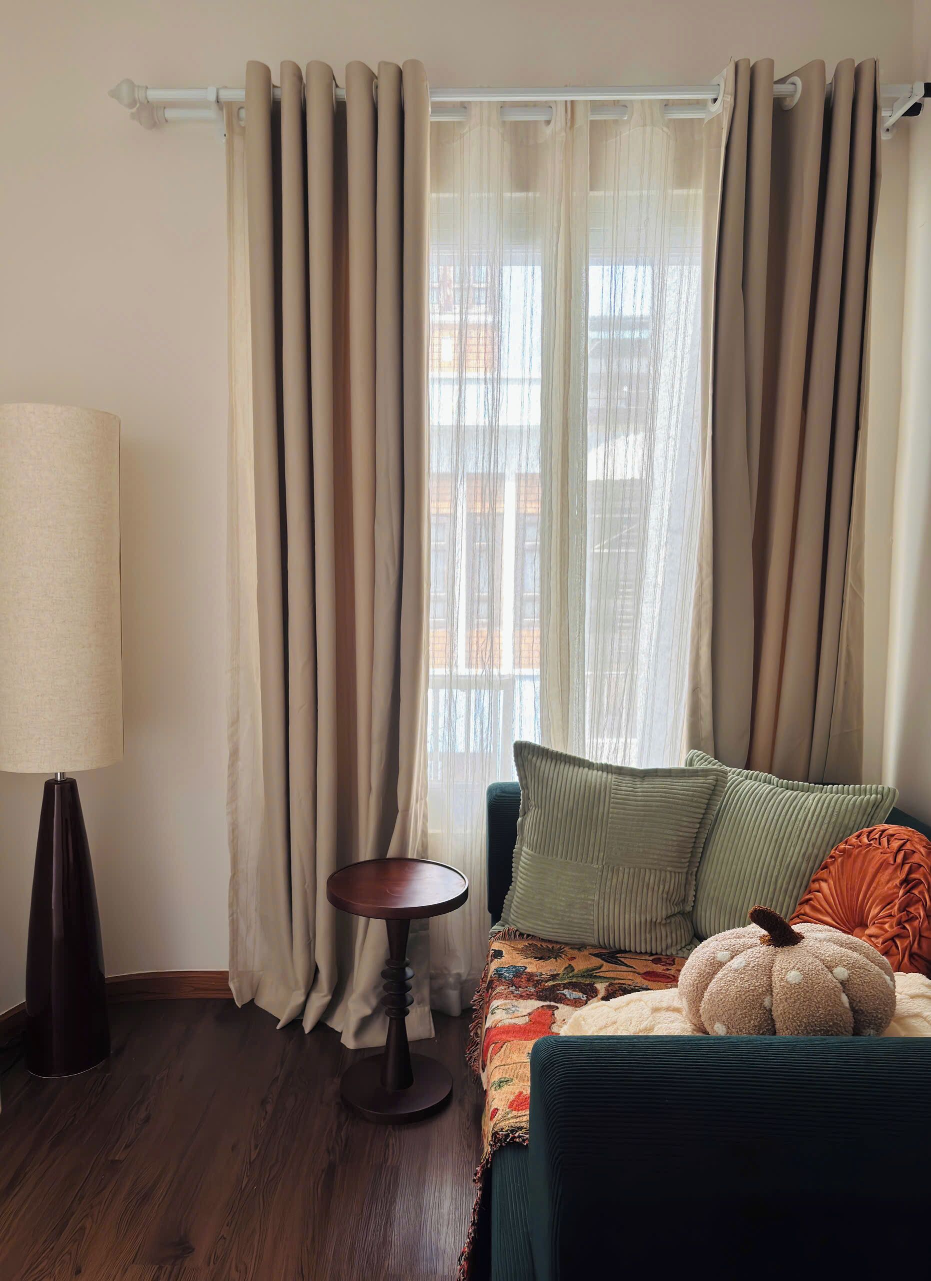 A room with a sofa, a lamp, a small table, and curtains.