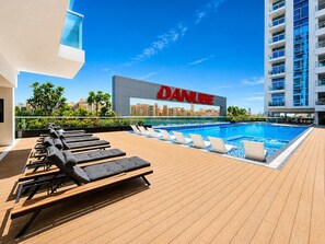 Ein Poolbereich auf dem Dach mit Liegestühlen, einem Pool und einem Gebäude mit der Aufschrift 'DANUBE'.