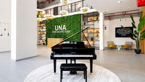 Um piano de cauda num hall espaçoso com parede verde e decoração moderna.