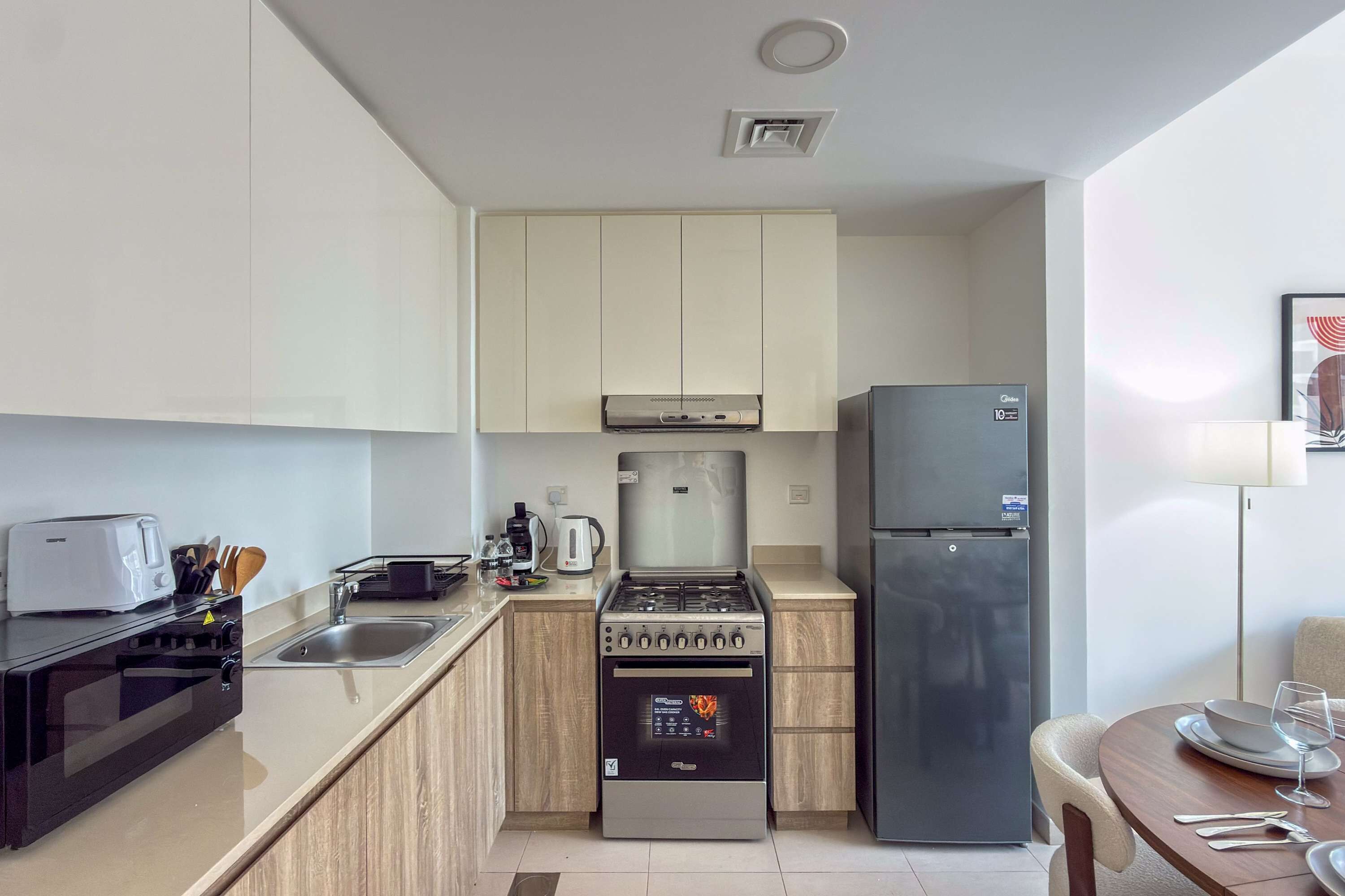 Eine kleine Küche mit Gasherd, Backofen, Kühlschrank und Toaster.