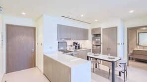 A modern kitchen with a central island, built-in appliances, and a dining area with a table and chairs. - Luxury 1BR at Grande | Cityscape Views, Downtown (Dubai)