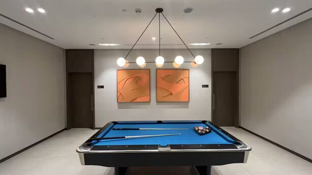 A pool table in a room with a modern ceiling design and abstract wall art. - Luxury 1BR at Grande | Cityscape Views, Downtown (Dubai)
