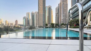 A swimming pool with a cityscape in the background. - Luxury 1BR at Grande | Cityscape Views, Downtown (Dubai)