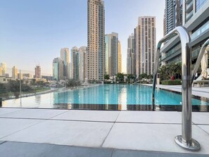 A swimming pool with a cityscape in the background. - Luxury 1BR at Grande | Cityscape Views, Downtown (Dubai)