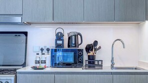 A modern kitchen with a microwave, coffee maker, and a gas stove. - Luxury 1BR at Grande | Cityscape Views, Downtown (Dubai)