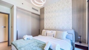 Ein modernes Hotelzimmer mit Bett, Nachttisch, Lampe, Kleiderschrank und einer Wand mit Muster.