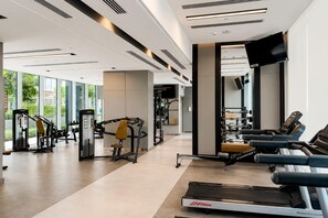 A modern gym with cardio equipment, weight machines, and a mirrored wall. - Harbour View 2BR - High Floor - Creek Harbour (Dubai)