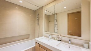 Ein modernes Badezimmer mit einem großen Spiegel, zwei Waschbecken und einer Dusche.