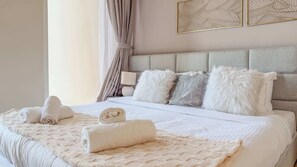 Un lit bien fait, avec des serviettes pliées, une couverture moelleuse et une tête de lit agrémentée de plusieurs coussins.