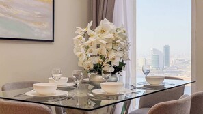 A dining table with white bowls, wine glasses, and a vase of white orchids. - Harbour View 2BR - High Floor - Creek Harbour (Dubai)