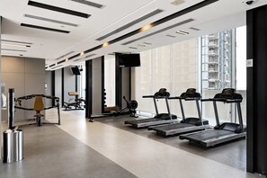 Une salle de sport moderne équipée de tapis de course, d’un rameur et d’un banc de musculation.
