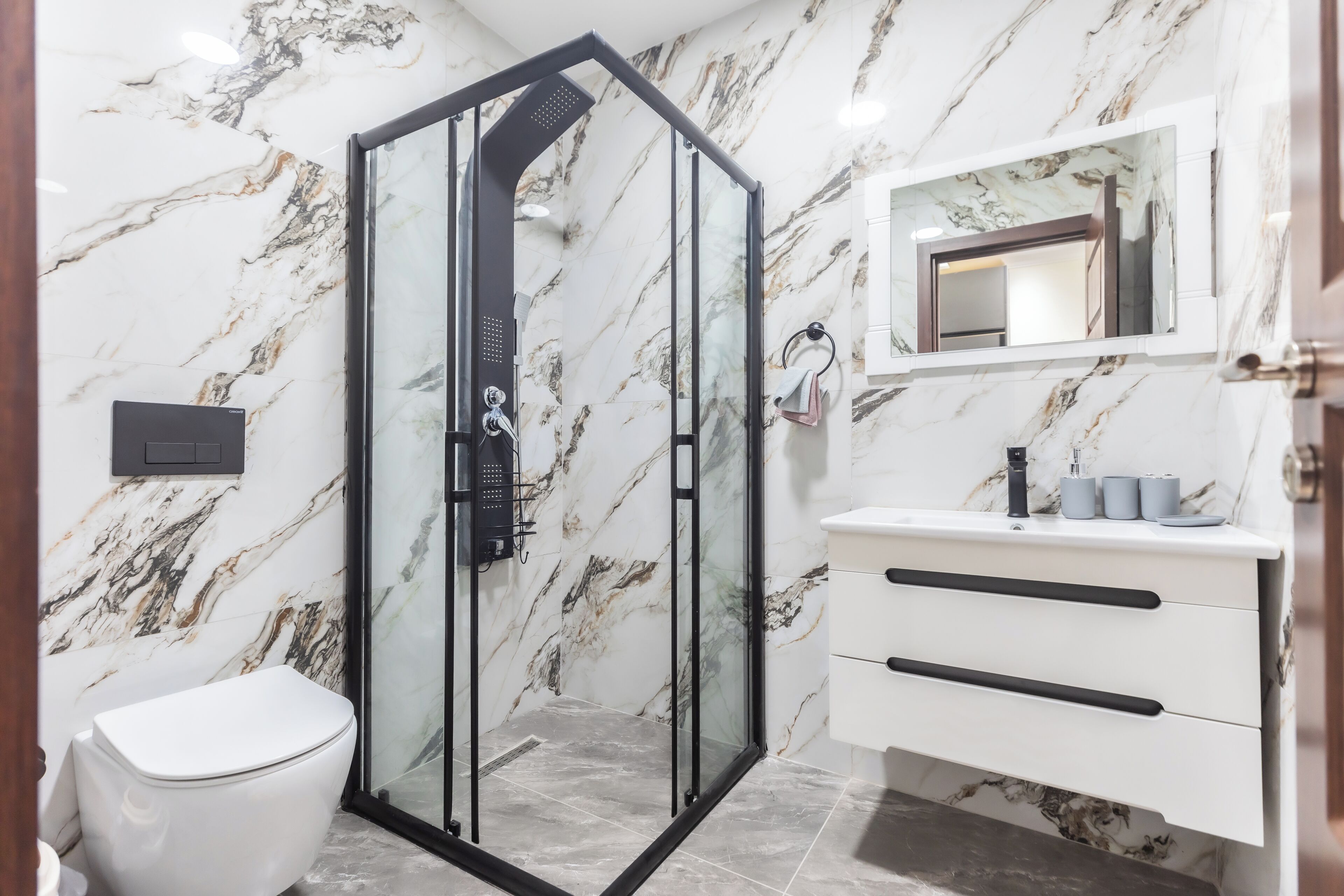 A bathroom with a glass-enclosed shower, a white toilet, and a vanity with a mirror.
