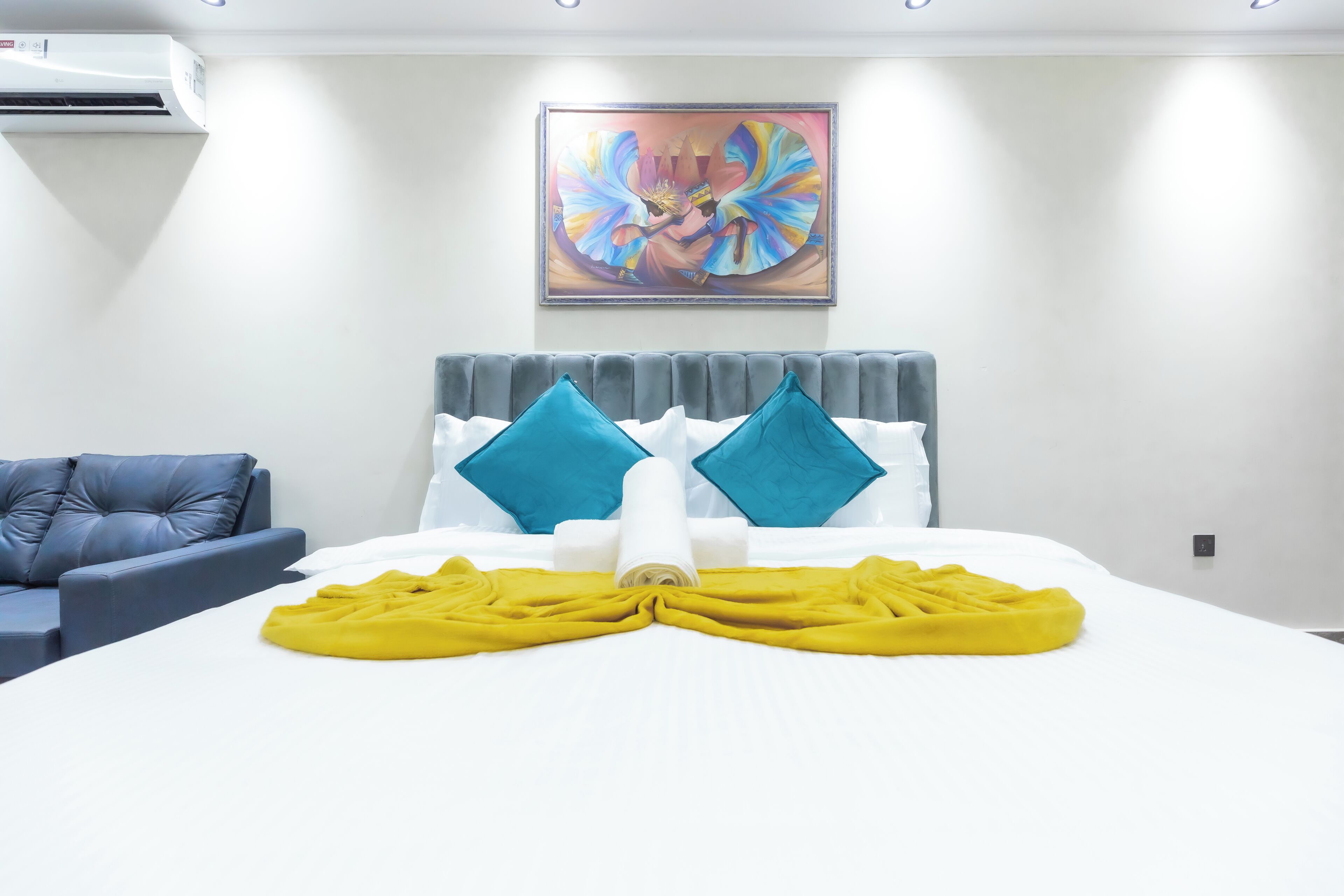 Ein Hotelzimmer mit einem Bett, einem grauen Sofa und einem Bild an der Wand.