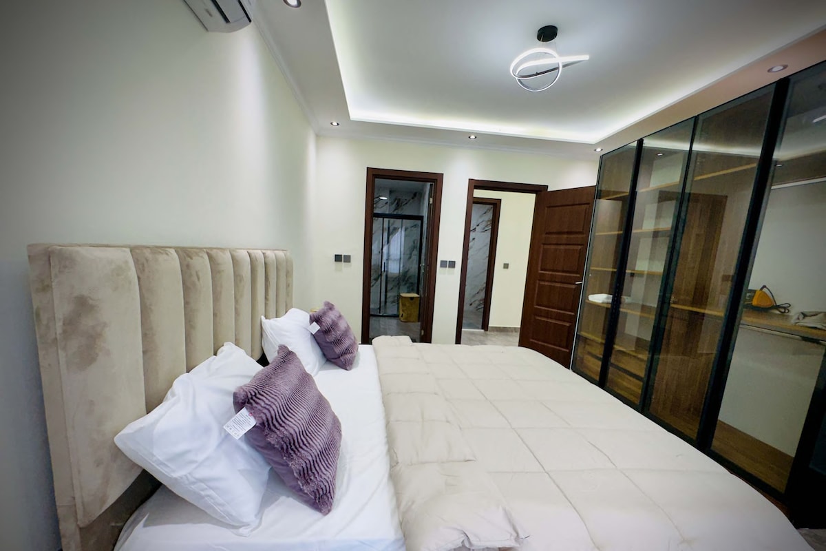 A hotel room with a bed, a wardrobe, and a door leading to another room.