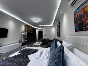 Habitació d'hotel moderna amb un llit, una taula de treball, zona de seients i un quadre al mur.