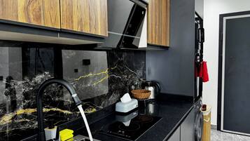 A modern kitchen with a black countertop, stainless steel sink, and wooden cabinets.