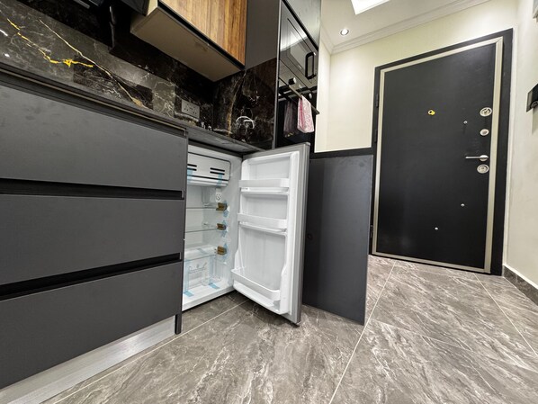 A modern kitchen with a built-in refrigerator, a black door, and marble flooring. - Floria 807B (Accra)