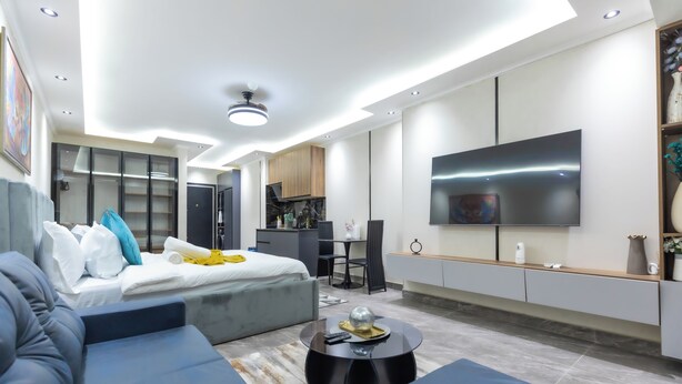 Une chambre d’hôtel moderne équipée d’un lit, d’un canapé, d’une télévision et d’une kitchenette.