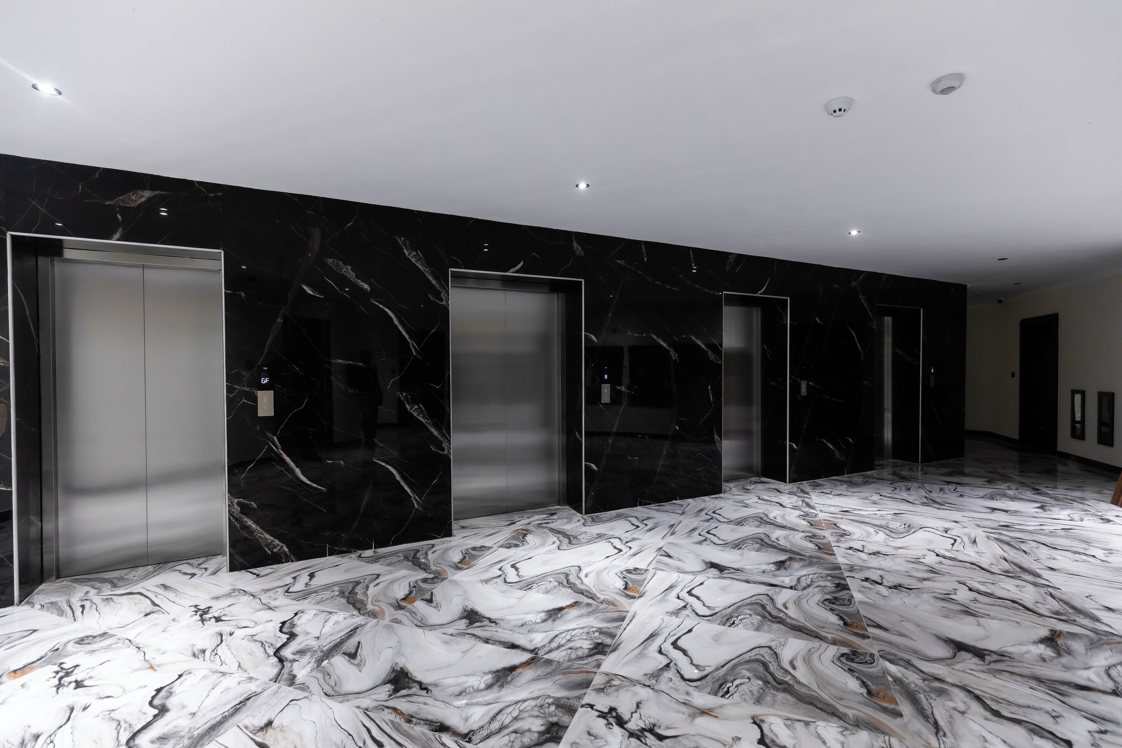 A hallway with marble flooring and elevator doors.