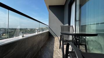 A balcony with a view of a cityscape, a table, and chairs.