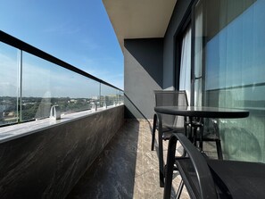 A balcony with a view of a cityscape, a table, and chairs. - Floria 807B (Accra)