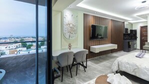 Une chambre d’hôtel moderne dotée d’un balcon, d’un coin repas, d’une télévision et d’une kitchenette.