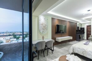 A modern hotel room with a balcony, a dining area, a TV, and a kitchenette. - Floria 807B (Accra)