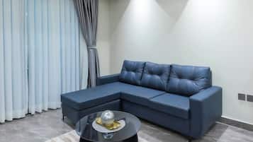 Una sala de estar moderna con un sofá modular, una mesa redonda de centro y un ventanal con cortinas.