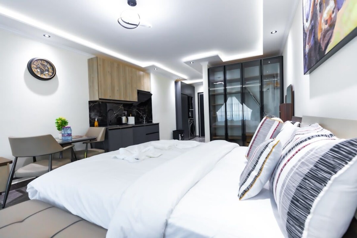 Una habitación de hotel moderna con una cama grande, un escritorio y vistas al exterior.