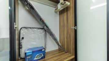 Una habitación con una puerta de madera, un estante metálico y una caja azul con la etiqueta 'Midea Electric Steam Iron'.