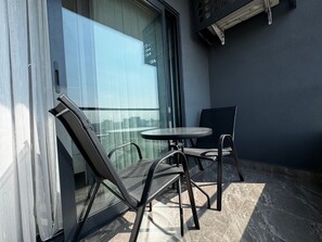 A balcony with a glass door, a round table, and two chairs.