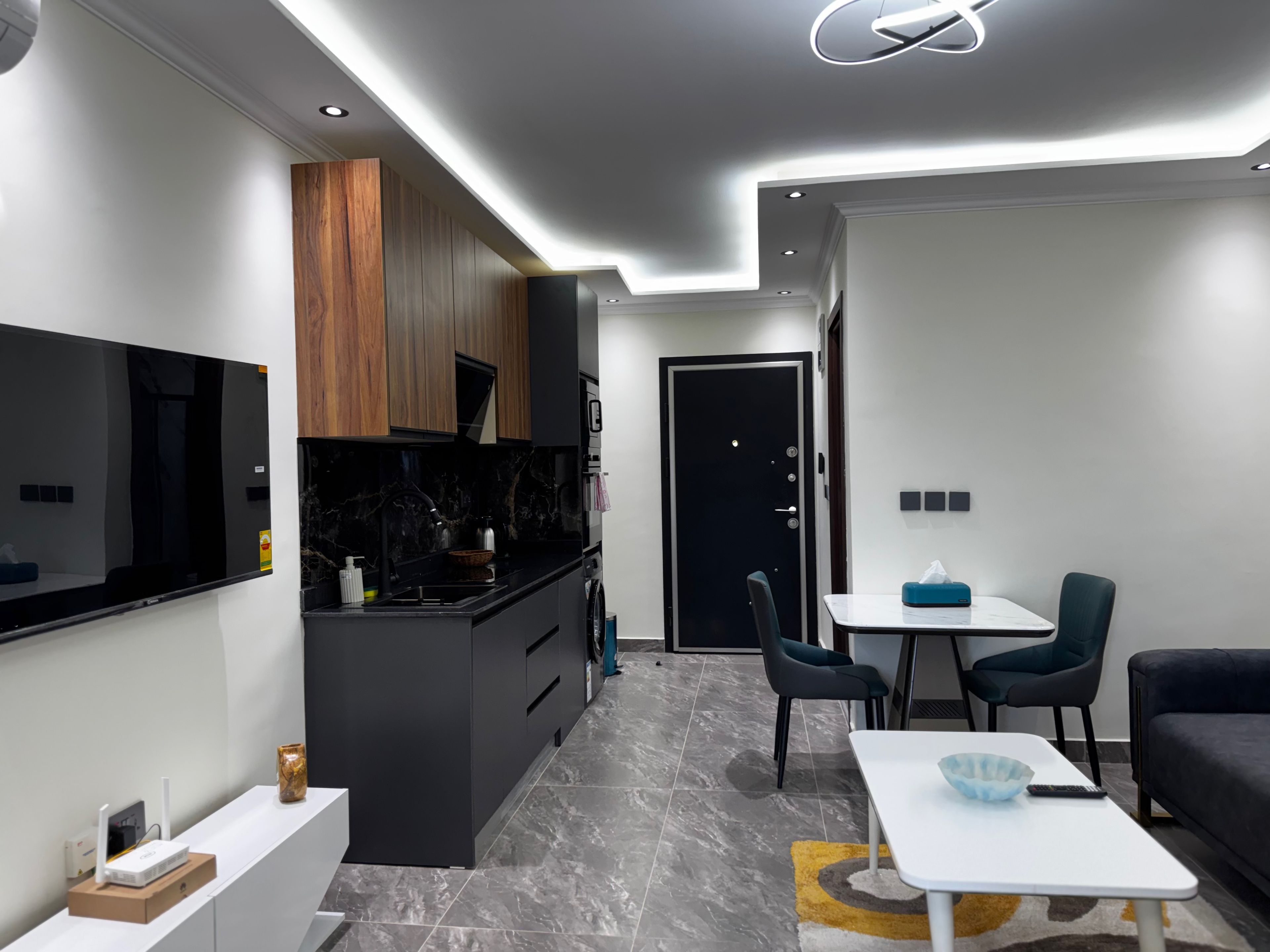 Een moderne keuken met een inbouwoven, een eethoek met een tafel en stoelen, en een woonkamer met een bank.