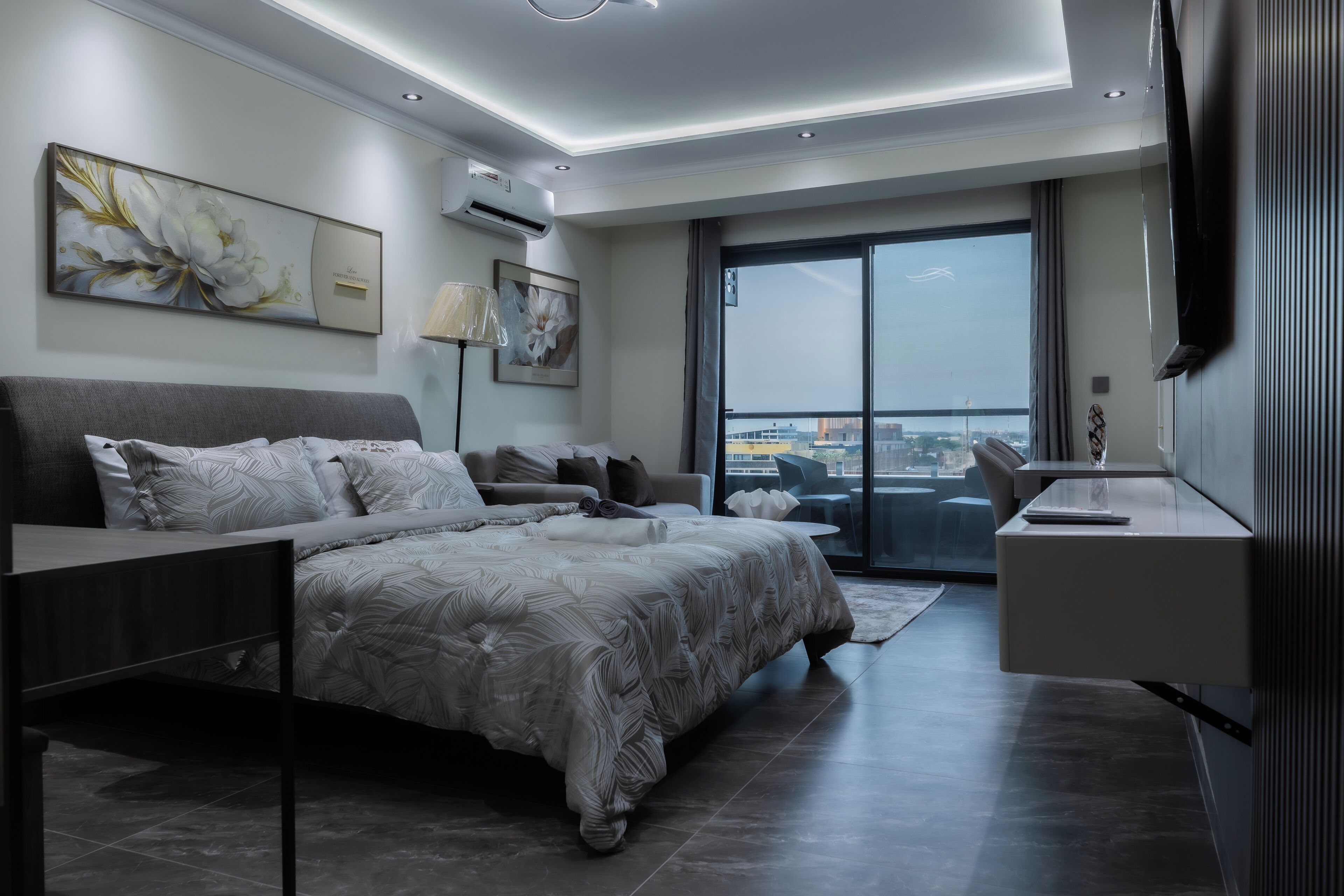 Een moderne slaapkamer met een groot bed, een bureau en uitzicht op de stad.