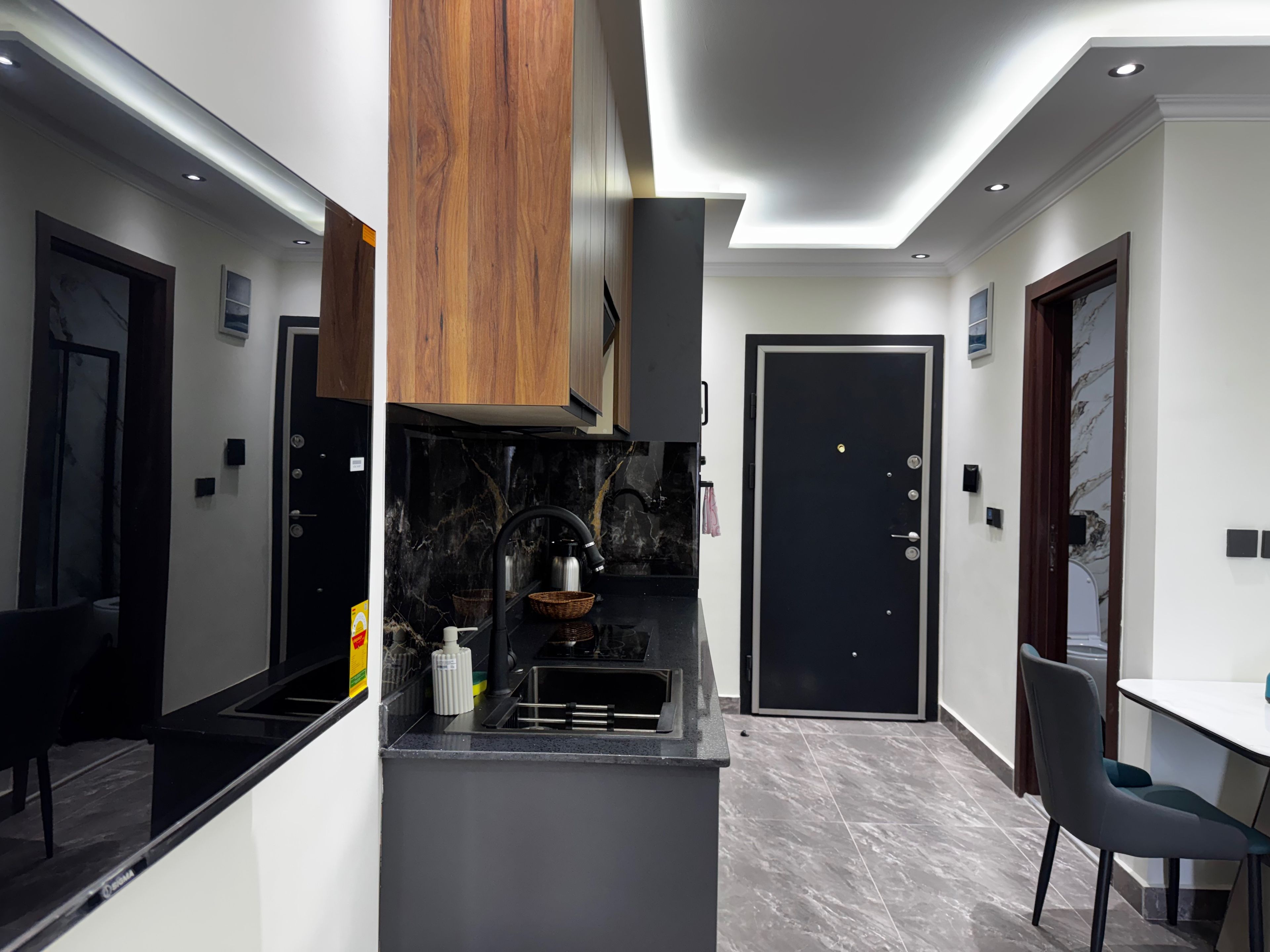 Una cocina moderna con encimera negra, armarios de madera y puerta negra.