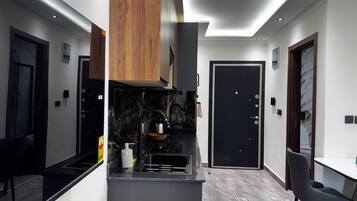 Una cocina moderna con encimera negra, armarios de madera y puerta negra.