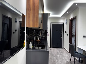 Una cocina moderna con encimera negra, armarios de madera y puerta negra.
