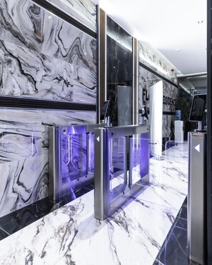 A modern lobby with marble walls and a glass barrier with purple lighting. - Floria 807B (Accra)