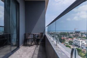 A balcony with a table and chairs, overlooking a cityscape with buildings and a crane. - Floria 807B (Accra)