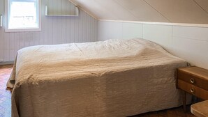 Ein Schlafzimmer mit einem Bett, einem Fenster und einem Nachttisch aus Holz.