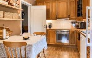 A kitchen with wooden cabinets, a stainless steel oven, and a dining table with chairs. - 5 bedroom lovely home in Syvde (Syvde)