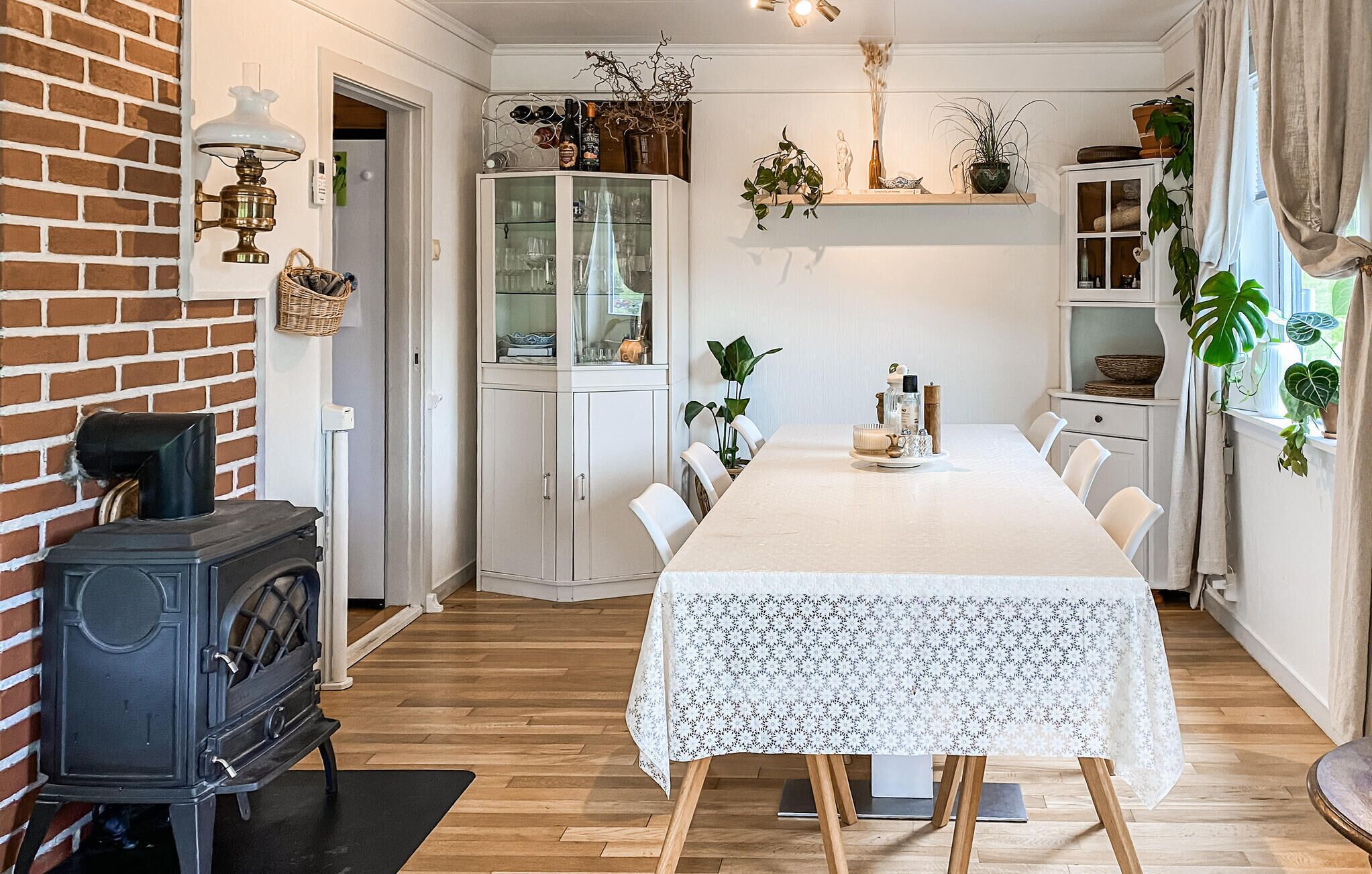A dining area with a long table, white cabinets, and a brick wall.