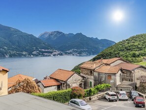 A coastal town with stone buildings, a parking area, and a view of the sea and mountains. - Casa Matilde by Interhome (Cremia)