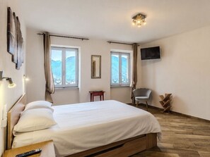 A bedroom with a bed, two windows, a chair, a TV, and a small table. - Casa Matilde by Interhome (Cremia)