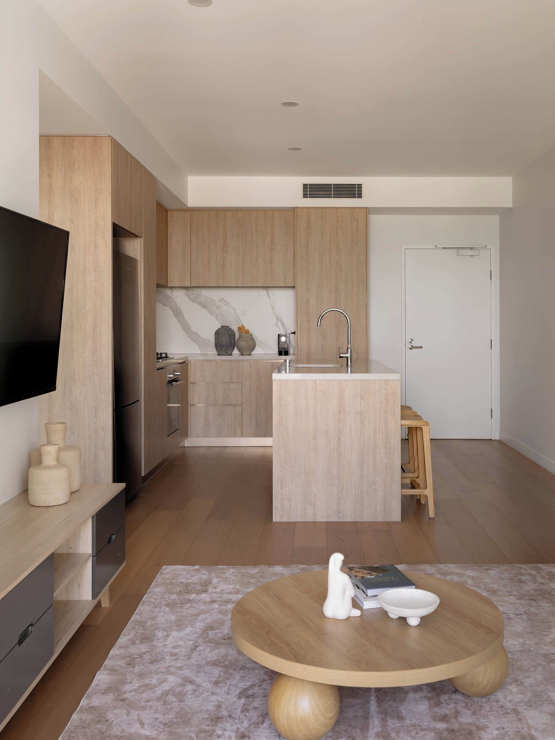 Una cocina moderna con armarios de madera, una isla integrada con un lavamanos y un televisor de pantalla plana montado en la pared.